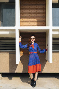 Portrait of woman standing against brick wall