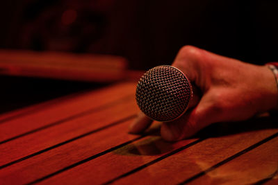 Cropped hand holding microphone on table