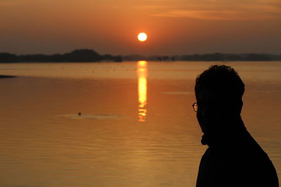 Silhouette man standing at beach during sunset