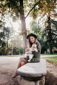 Portrait of a smiling young woman sitting against trees