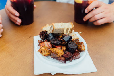 Cropped hand holding disposable cups with drinks by food on table