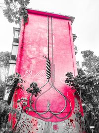 Low angle view of pink flowering plant against building