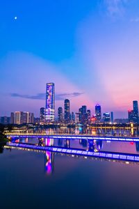 Illuminated buildings against blue sky at night