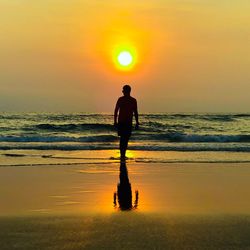 Silhouette man standing on beach against sky during sunset