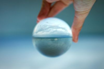 Cropped hand holding crystal ball with reflection of sea