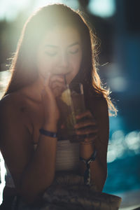 Young woman having drink on sunny day
