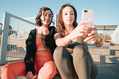 Smiling females friends taking selfie sitting outdoors