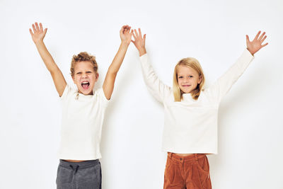 Cheerful sibling with arms raised against white background