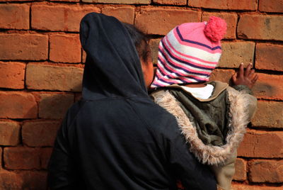 Midsection of woman standing against brick wall