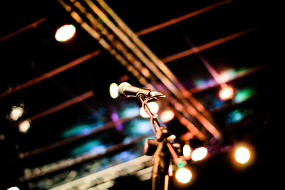 Low angle view of illuminated lighting equipment at night