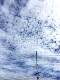 Low angle view of power lines against cloudy sky