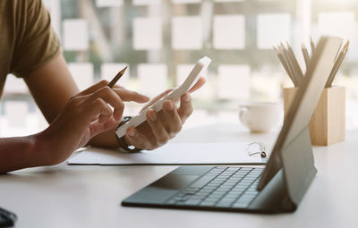 Midsection of woman using laptop at table