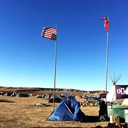 Flags on landscape against clear blue sky