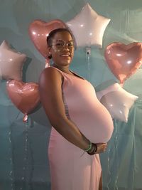 Midsection of man with balloons standing in illuminated mirror