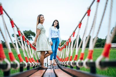 Full length of woman standing on railing against sky