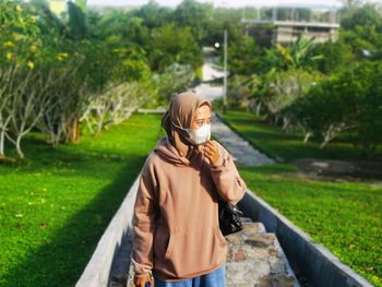 Portrait of young woman standing against trees