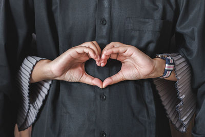 Midsection of man making heart shape