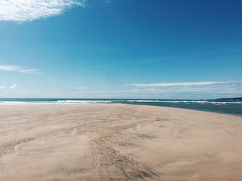 Scenic view of beach against blue sky