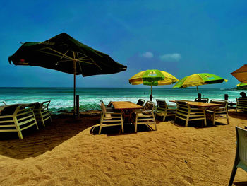 Lounge chairs and parasols on beach against sky