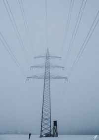 Low angle view of electricity pylon against sky during winter