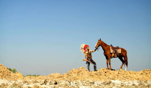 Full length of man wearing costume with horse against sky