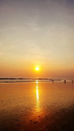 Scenic view of beach against dramatic sky during sunset