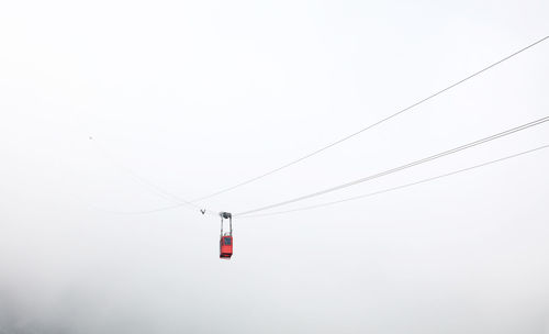 Low angle view of overhead cable car during foggy weather