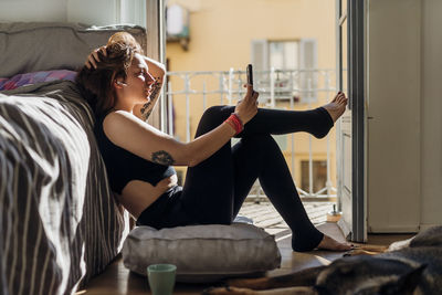 Woman with hand in hair taking selfie through mobile phone at home