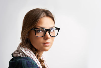 Portrait of young woman wearing sunglasses against white background