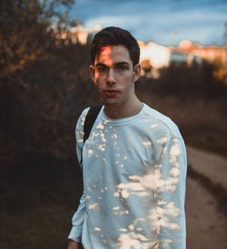 Young man standing outdoors on sunny day