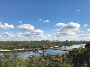 Bridge over river in city against cloudy sky