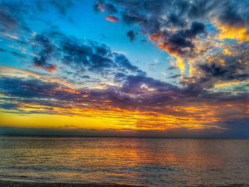 Scenic view of sea against dramatic sky during sunset