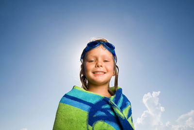 Portrait of happy girl covered with towel against sky