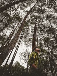 Low angle view of woman standing by tree in forest