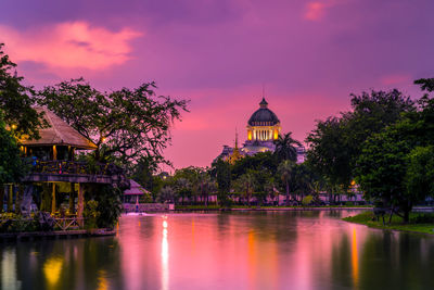 View of building by lake at sunset