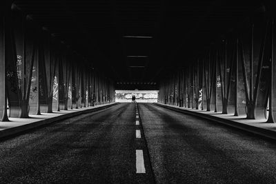 Empty road under metallic bridge in city