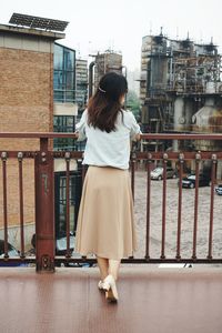 Rear view of woman standing against railing in city