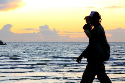 Silhouette man walking on shore during sunset