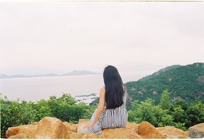 Rear view of woman looking at mountains against sky