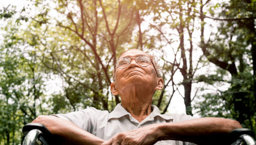 Portrait of man with umbrella against trees