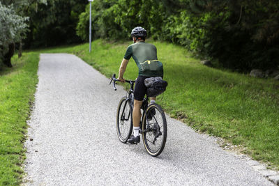 Rear view of man riding bicycle on road