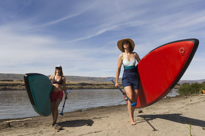 Two women carry their sups from the columbia river in oregon.