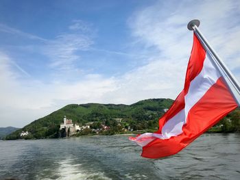 Red flag on lake against sky