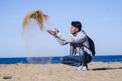 Man with umbrella on beach against clear sky