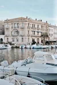 Boats moored in canal by buildings in city against sky