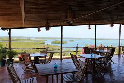 Empty chairs and tables in restaurant against sky