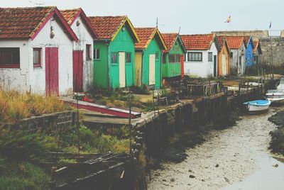 Multi colored houses on beach by buildings against sky