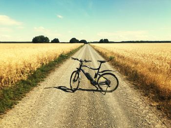 Bicycle on road amidst field