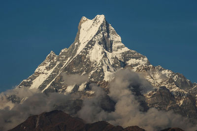 Low angle view of snowcapped mountain against blue sky