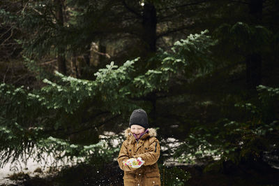 Person standing by tree against plants during winter